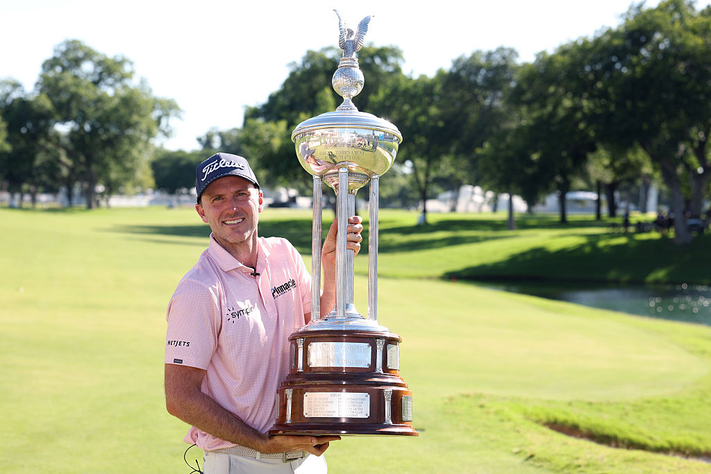 Russell Henley holding the Charles Schwab Challenge trophy on the golf course